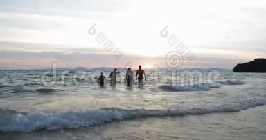 一群人在日落时分从海上奔跑，快乐的年轻朋友在沙滩上度过暑假